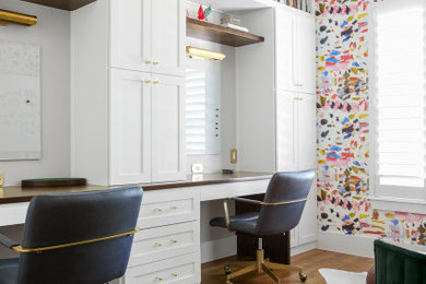 ダラスにある高級な中くらいなエクレクティックスタイルのおしゃれな書斎 (白い壁、無垢フローリング、造り付け机、壁紙、茶色い床) の写真