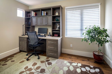 Modelo de despacho clásico de tamaño medio sin chimenea con paredes beige, suelo de madera en tonos medios y escritorio independiente