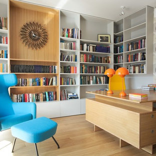Idéer för att renovera ett funkis arbetsrum, med ett bibliotek, flerfärgade väggar, mellanmörkt trägolv, ett inbyggt skrivbord och gult golv