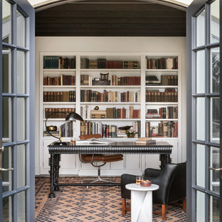 Medelhavsstil inredning av ett hemmabibliotek, med vita väggar och ett fristående skrivbord