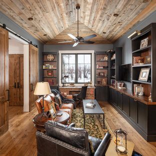 Landhaus Arbeitszimmer mit grauer Wandfarbe, braunem Holzboden, freistehendem Schreibtisch und braunem Boden in Salt Lake City