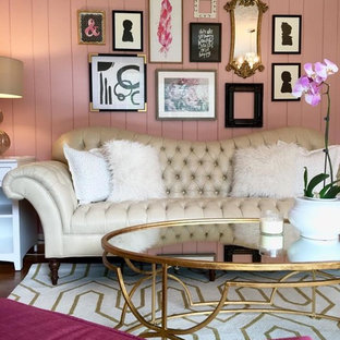 Bild på ett stort vintage hemmabibliotek, med rosa väggar, mellanmörkt trägolv och ett fristående skrivbord