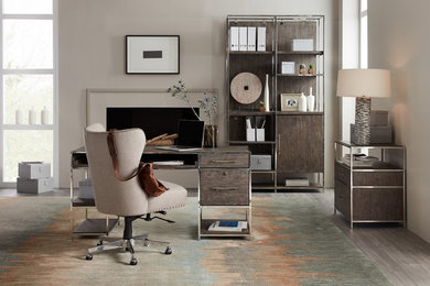 Ejemplo de despacho actual grande con paredes beige, suelo de baldosas de porcelana, todas las chimeneas, marco de chimenea de yeso, escritorio independiente y suelo gris