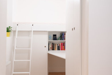 Imagen de despacho contemporáneo pequeño con paredes blancas, suelo de madera en tonos medios, escritorio empotrado, suelo marrón y biblioteca