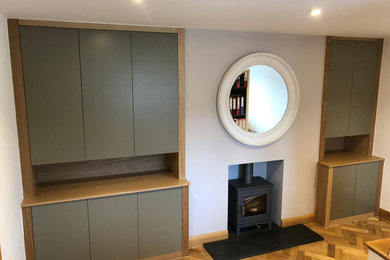 Photo of a medium sized modern study in Essex with white walls, medium hardwood flooring, a wood burning stove and a built-in desk.