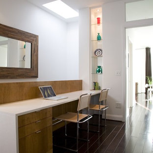 Trendy built-in desk dark wood floor home office photo in DC Metro with white walls