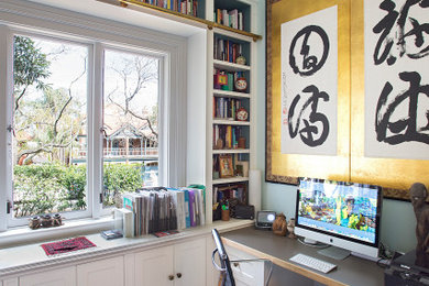 Imagen de despacho de tamaño medio con paredes blancas, suelo de madera oscura, escritorio empotrado y panelado