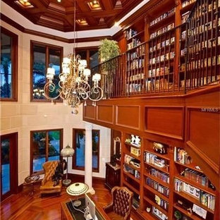 Inspiration för mycket stora klassiska arbetsrum, med ett bibliotek, bruna väggar, mellanmörkt trägolv, en spiselkrans i sten och ett fristående skrivbord