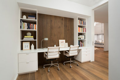 Exemple d'un grand bureau tendance avec un mur blanc, un sol en bois brun, aucune cheminée, un bureau intégré et un sol beige.