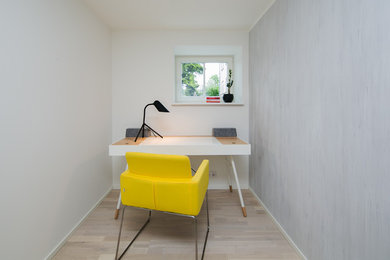 Ejemplo de despacho nórdico pequeño con paredes grises, suelo de madera en tonos medios y escritorio independiente