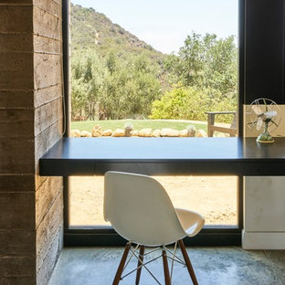 Kleines Klassisches Arbeitszimmer ohne Kamin mit weißer Wandfarbe, Betonboden, Arbeitsplatz, Einbau-Schreibtisch und braunem Boden in Los Angeles