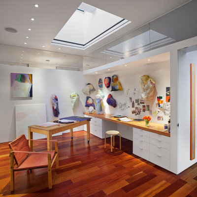 Trendy built-in desk medium tone wood floor home studio photo in New York with white walls and no fireplace