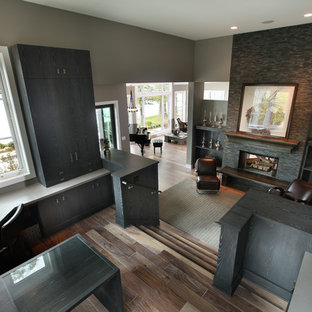 Exemple d'un grand bureau tendance avec un bureau intégré, un mur gris, un sol en bois brun, une cheminée standard et un manteau de cheminée en pierre.