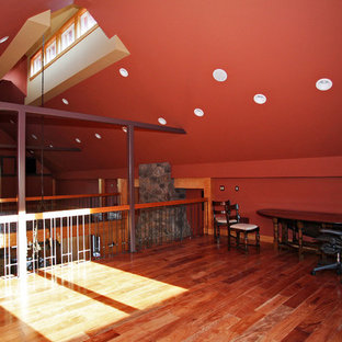 Cette image montre un grand bureau chalet avec un mur violet, un sol en bois brun, une cheminée standard, un manteau de cheminée en pierre et un bureau indépendant.