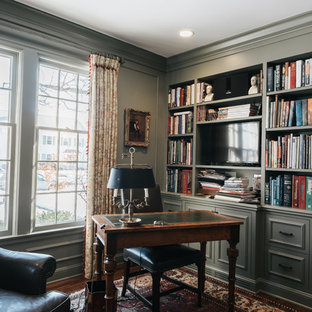 Cette image montre un bureau traditionnel de taille moyenne avec un mur vert, un sol en bois foncé, une cheminée standard, un manteau de cheminée en bois et un bureau indépendant.