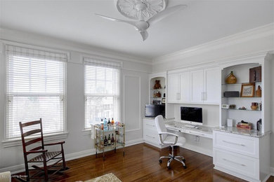 Inspiration for a mid-sized transitional built-in desk medium tone wood floor home office remodel in Louisville with white walls