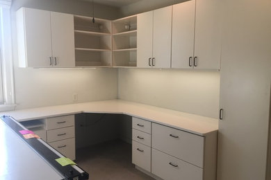 Diseño de despacho minimalista de tamaño medio con paredes blancas, moqueta, escritorio empotrado y suelo beige