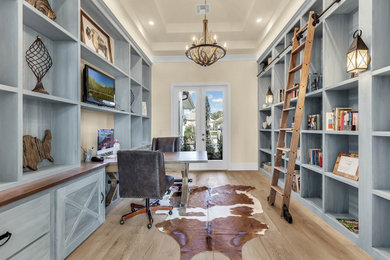 Imagen de despacho clásico renovado grande con paredes grises, suelo de madera clara, escritorio empotrado y suelo gris