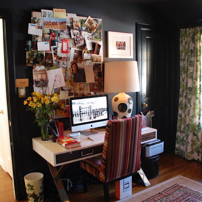 Home office - eclectic freestanding desk dark wood floor and brown floor home office idea in Los Angeles with black walls