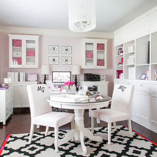 Foto på ett stort funkis hemmastudio, med rosa väggar, mörkt trägolv och ett fristående skrivbord