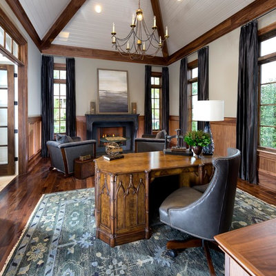 Inspiration for a mid-sized mediterranean freestanding desk dark wood floor and brown floor home office library remodel in Nashville with beige walls, a standard fireplace and a wood fireplace surround