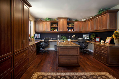 Modelo de despacho clásico grande sin chimenea con paredes beige, suelo de madera oscura y escritorio empotrado