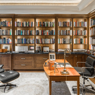 Large elegant freestanding desk medium tone wood floor and brown floor home office library photo in Boston with gray walls and no fireplace