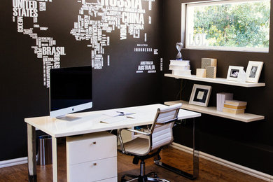 Diseño de despacho actual de tamaño medio con paredes verdes, suelo de madera en tonos medios y escritorio independiente