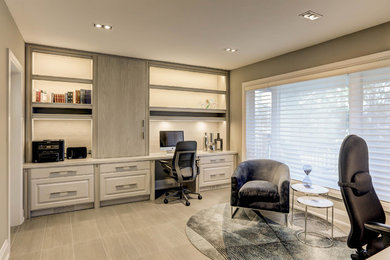 Imagen de despacho actual grande sin chimenea con paredes beige, suelo laminado, escritorio empotrado y suelo beige