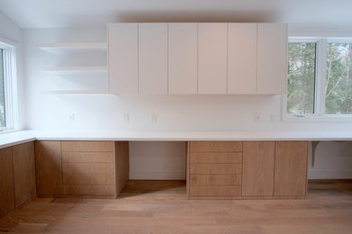 Mittelgroßes Modernes Arbeitszimmer ohne Kamin mit Studio, weißer Wandfarbe, braunem Holzboden und Einbau-Schreibtisch in New York