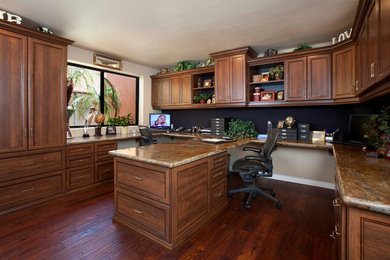 Modelo de despacho clásico de tamaño medio sin chimenea con paredes beige, suelo de madera oscura y escritorio empotrado