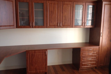 Modelo de despacho actual grande con paredes blancas, suelo de madera en tonos medios y escritorio empotrado