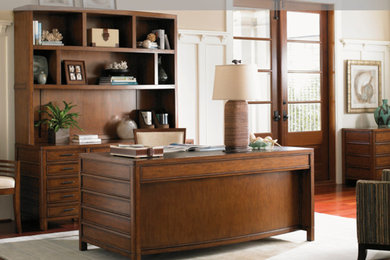 Diseño de despacho de estilo americano grande con escritorio independiente, paredes beige y suelo de madera en tonos medios