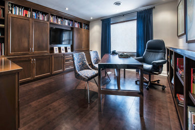 Mittelgroßes Klassisches Arbeitszimmer ohne Kamin mit Arbeitsplatz, freistehendem Schreibtisch, grauer Wandfarbe und dunklem Holzboden in Toronto