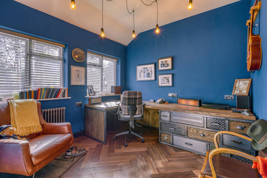 Ejemplo de despacho industrial con paredes azules, suelo de madera oscura, escritorio empotrado y suelo marrón