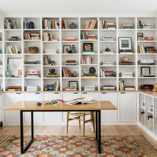 Modernes Arbeitszimmer mit weißer Wandfarbe, hellem Holzboden, freistehendem Schreibtisch und beigem Boden in Boston