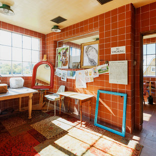 Cette image montre un bureau atelier rustique de taille moyenne avec un mur rouge, un sol en carreau de terre cuite, aucune cheminée, un bureau indépendant et un sol rouge.