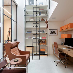 This is an example of a contemporary home office in London with white walls, a built-in desk and grey floors.