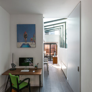 Modelo de despacho contemporáneo, pequeño, con paredes blancas, suelo de madera oscura y escritorio independiente