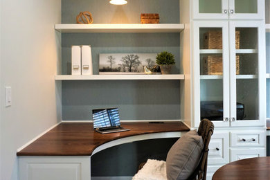 Diseño de despacho tradicional renovado de tamaño medio con paredes blancas, suelo de madera en tonos medios, escritorio empotrado y suelo marrón
