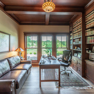 Bild på ett litet amerikanskt arbetsrum, med ett bibliotek, beige väggar, ljust trägolv, ett fristående skrivbord och gult golv