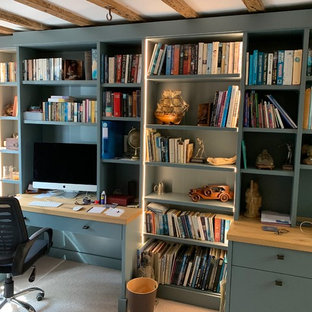 Inredning av ett modernt stort hemmabibliotek, med beige väggar, heltäckningsmatta, en hängande öppen spis, en spiselkrans i tegelsten, ett inbyggt skrivbord och beiget golv