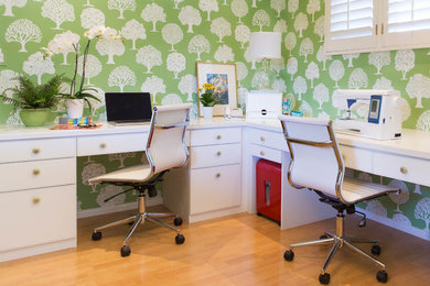 Transitional built-in desk medium tone wood floor and brown floor home office photo in Other with green walls