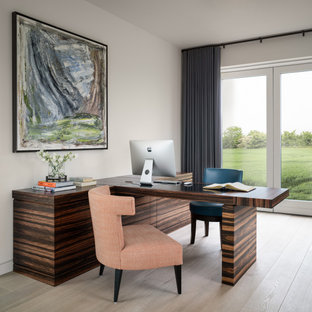 Medium sized contemporary study in Other with white walls, light hardwood flooring, a built-in desk and beige floors.