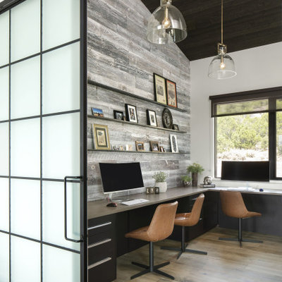 Inspiration for a large industrial built-in desk light wood floor, brown floor, vaulted ceiling and wood wall home studio remodel in Denver with white walls