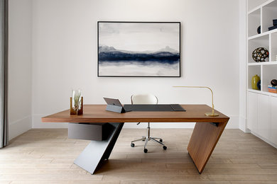 Photo of a modern study in Other with white walls, light hardwood flooring, a freestanding desk and beige floors.