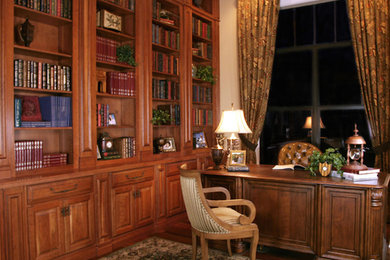 Imagen de despacho clásico grande con paredes beige, suelo de madera oscura y escritorio independiente