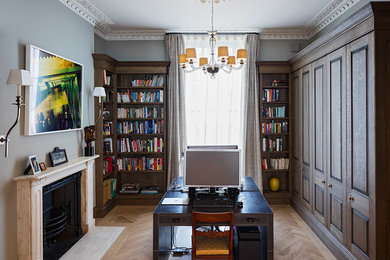 ロンドンにあるラグジュアリーな広いトラディショナルスタイルのおしゃれな書斎 (グレーの壁、淡色無垢フローリング、標準型暖炉、石材の暖炉まわり、自立型机) の写真