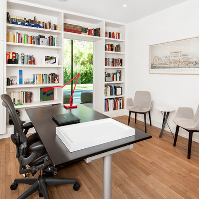 Home office - contemporary freestanding desk medium tone wood floor home office idea in Austin with white walls