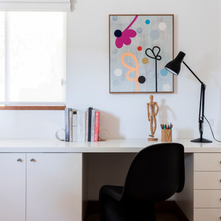 Inspiration for a mid-sized midcentury study room in Sydney with white walls, travertine floors, a built-in desk and brown floor.